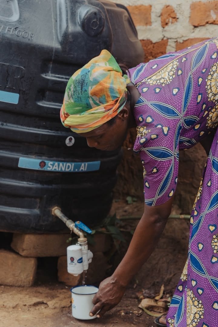 A woman filling a cup from a SandiLyt water tank