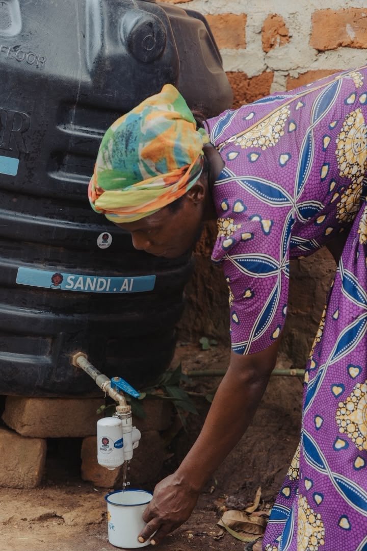 A woman collecting filtered water from a SandiLyt tank