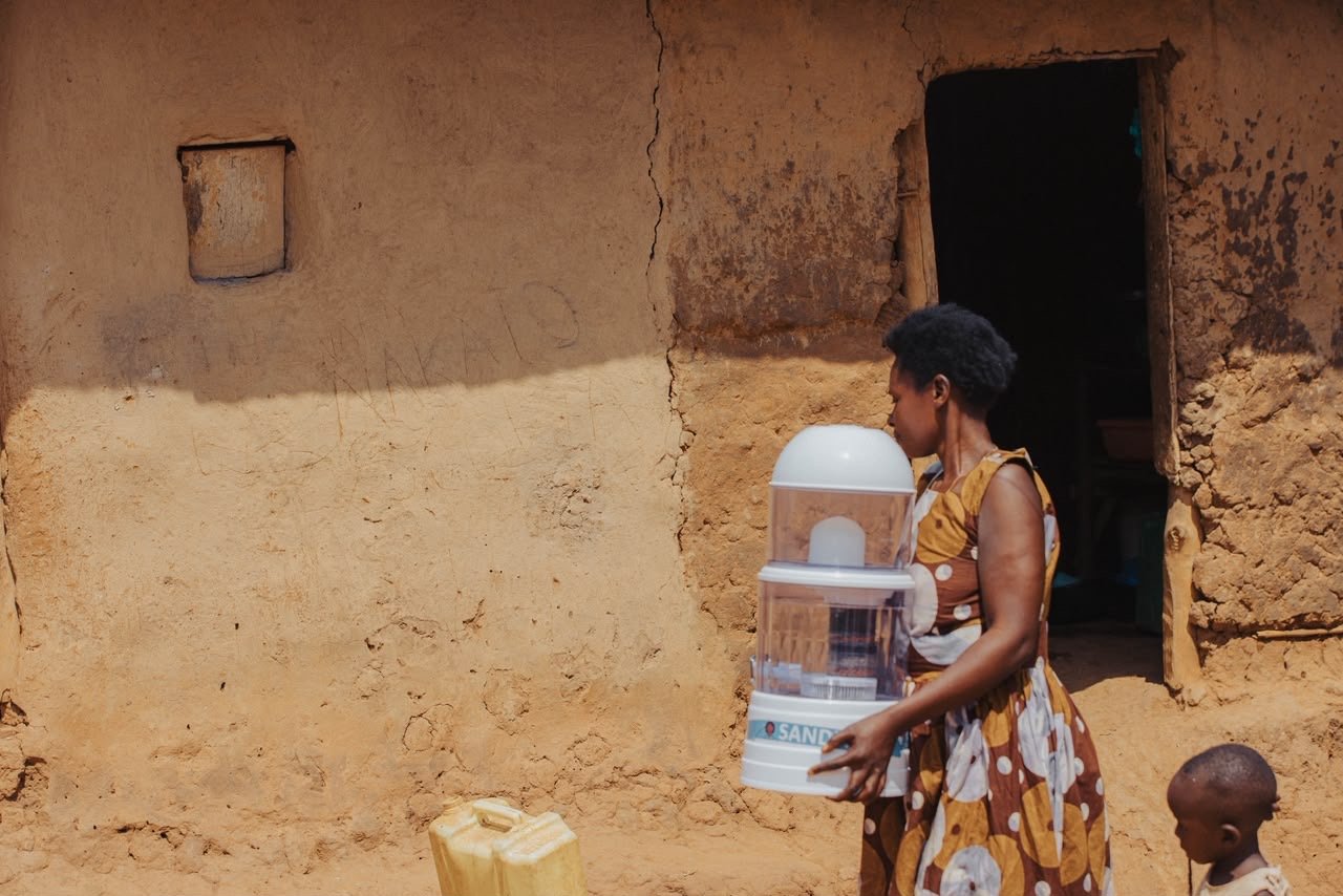 A mother carrying her new SandiLyt water purifier home