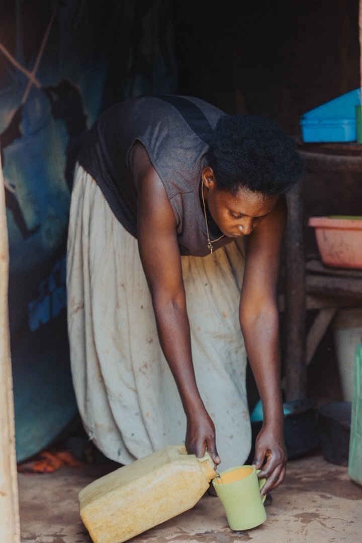 A woman pouring water from a container into a cup at home