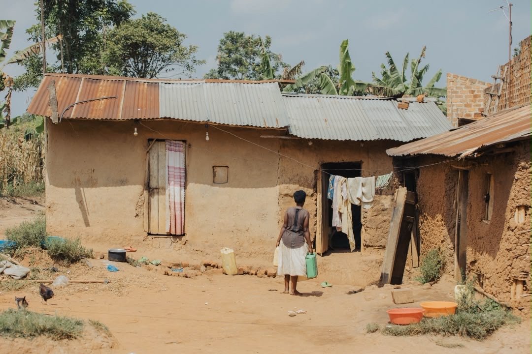 A woman returning home with water containers