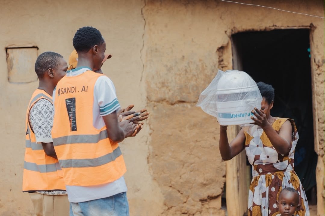 A mother receiving a packaged water purifier from the SandiLyt team