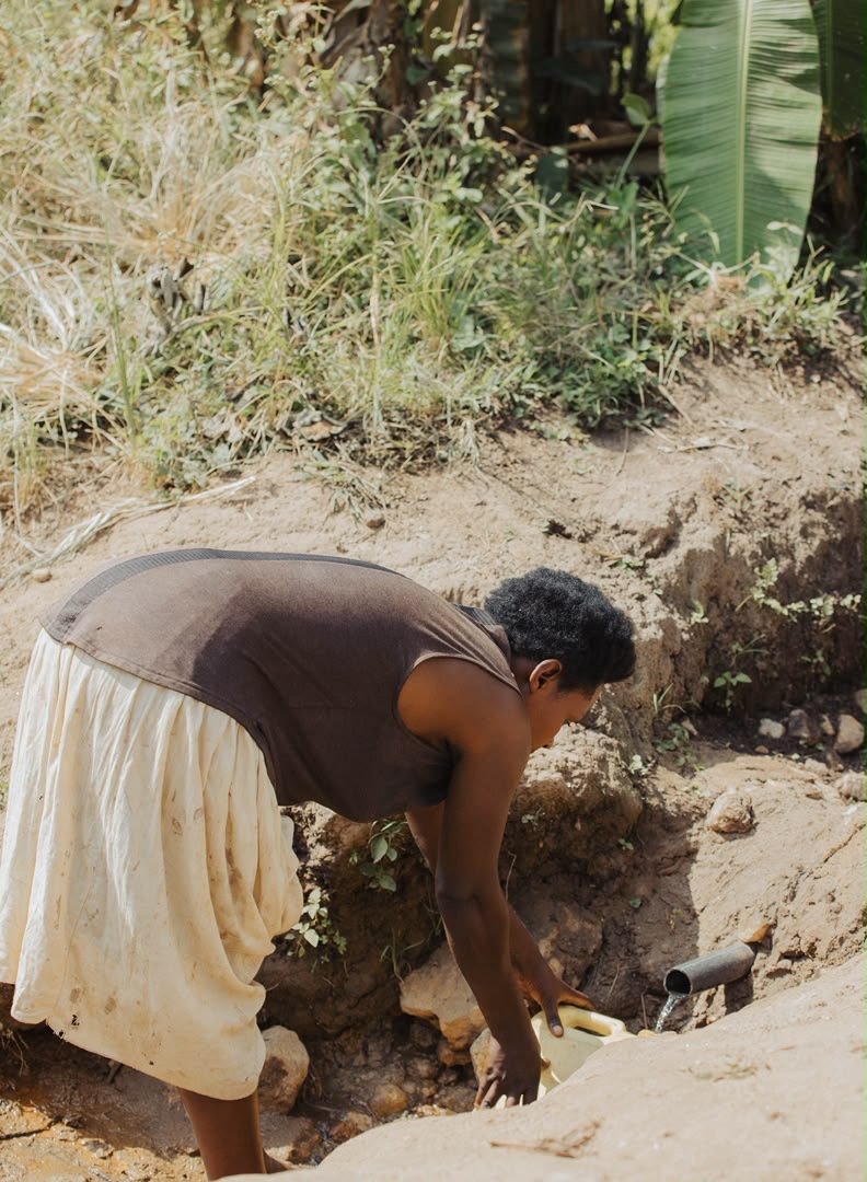 A woman filling a container at a rural water source